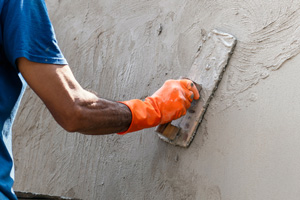 Arbeiter glättet Betonwand mit einer Maurerkelle.